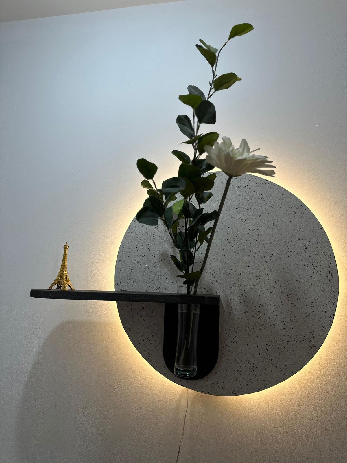 estante circular iluminado con florero y mini torre eiffel